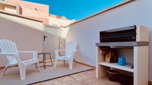 dwa białe krzesła i stół na patio w obiekcie Click&Guest - Alisios House in Las Palmas w mieście Las Palmas de Gran Canaria
