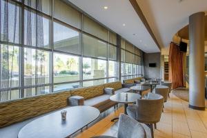 SpringHill Suites Tampa North/Tampa Palms في تامبا: مطعم بطاولات وكراسي ونوافذ كبيرة