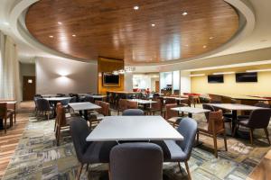 un restaurant avec des tables et des chaises et un grand plafond dans l'établissement SpringHill Suites Louisville Downtown, à Louisville