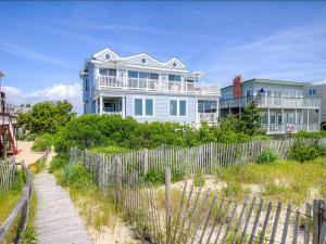 a large house on the beach next to a fence at Beautifully Renovated Ocean Front Home In Harvey Cedars in Harvey Cedars