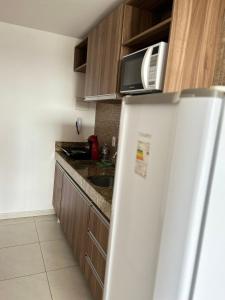 eine Küche mit einem weißen Kühlschrank und einer Mikrowelle in der Unterkunft Flat com localização privilegiada in Campina Grande