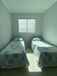 2 camas en una habitación con ventana en Apartamento à 100 metros da Praia Dos Ingleses, en Florianópolis