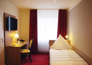 a hotel room with a bed and a desk and a window at Hotel Mühleneck in Schortens