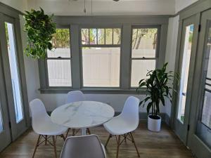 Entire home in Historic Long Beach close to shops في لونغ بيتش: طاولة وكراسي في غرفة بها نوافذ