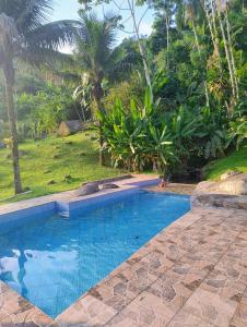 a swimming pool in front of a yard with trees at Pousada Porto Taquari in Paraty