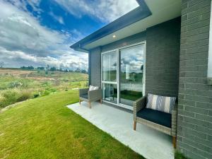 eine Terrasse mit einer Bank und einem Fenster zum Haus in der Unterkunft Maple Retreat by Blue Spring in Putaruru