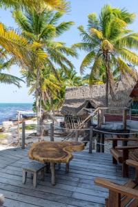 a wooden table and benches on a beach with palm trees at Grand Titanic, Boat House in Punta Allen