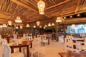 a restaurant with wooden tables and white chairs at Grand Titanic, Boat House in Punta Allen