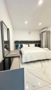 - une chambre avec un lit blanc et un miroir dans l'établissement Residence Roume Abidjan Plateau, à Abidjan