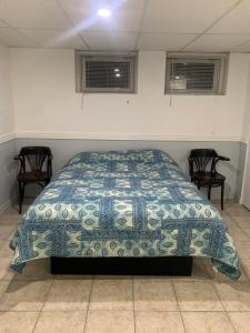 um quarto com uma cama com uma colcha azul e branca em La Maison Tanguay em Saguenay