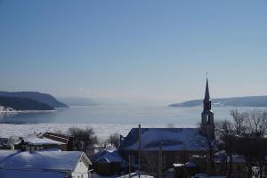 a small town with a church and a body of water at La Maison Tanguay in Saguenay