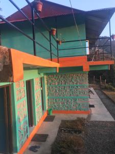 budynek w kolorze pomarańczowym i zielonym w obiekcie Sunrise Point Homestay w mieście Nagarkot
