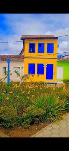 une maison jaune avec des fenêtres bleues dans une cour dans l'établissement Hostel do Coreto, à Mucugê