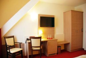 a room with a desk with chairs and a tv at Hotel Mühleneck in Schortens