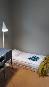 a bedroom with a bed and a desk and a lamp at Entisajan Helmi in Tampere