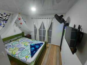 a small bedroom with a bed and a television at Villa Kerly Hotel en La Unión Valle in Lemos