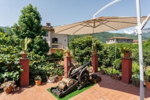 a garden with a cannon and an umbrella at Appartamento in villa liberty in Ghivizzano