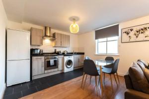 a kitchen with a table and a white refrigerator at Jasper- 2 Bed Flat With Parking in Southampton