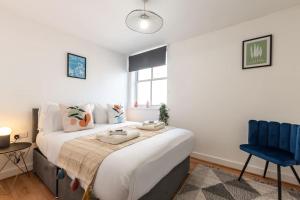 a bedroom with a large bed and a blue chair at Jasper- 2 Bed Flat With Parking in Southampton