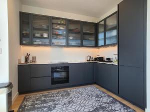 una cocina con armarios negros y alfombra en Cozy Room with Private Bathroom in Luxurious Flat, en Londres