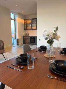 a table with plates and glasses and a vase of flowers at Cozy Room with Private Bathroom in Luxurious Flat in London