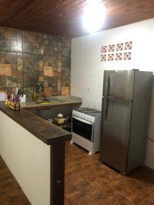 eine Küche mit einem Kühlschrank aus Edelstahl und einem Herd in der Unterkunft Casa de Família com Ar Condicionado, Garagem e Pet friendly in Búzios