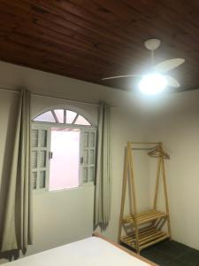1 dormitorio con ventilador de techo y ventana en Casa de Família com Ar Condicionado, Garagem e Pet friendly, en Búzios