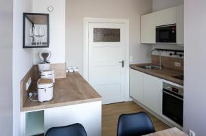 a kitchen with white cabinets and a counter with two blue chairs at Mollibahnhof - Kühlungsborn West Mollibahnhof West - Ferienwohnung in Kühlungsborn +2 photos