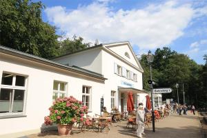 a man standing in front of a white building at Mollibahnhof - Heiligendamm Mollibahnhof Heiligendamm DZ 04 in Heiligendamm