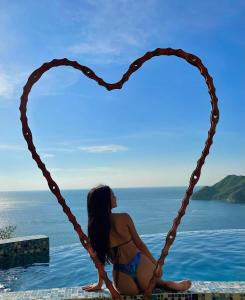 una mujer en bikini sentada en forma de corazón en Hotel TNT Mirador, en Taganga