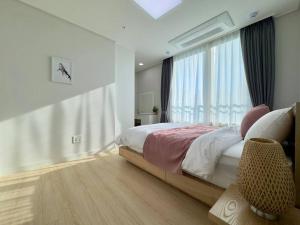 a bedroom with a bed and a large window at Eunhasu D&M Residence Haetsal 4 in Daejeon