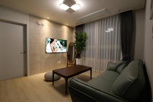 sala de estar con sofá y TV en la pared en Eunhasu D&M Residence Haetsal 4, en Daejeon