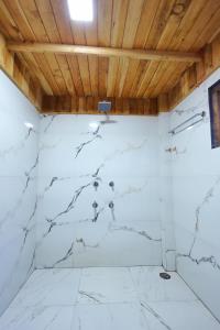 Pokój z białymi marmurowymi ścianami i drewnianymi sufitami w obiekcie Himalayan Cedar Nest w mieście Sainj