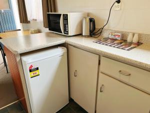 a kitchen counter with a microwave and a refrigerator at Cumberland Motel in Dunedin