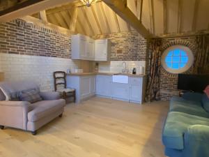 a living room with a couch and a kitchen at The Cowshed - converted barn/dairy in Felbridge