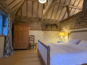 a bedroom with a large bed and a brick wall at The Cowshed - converted barn/dairy in Felbridge