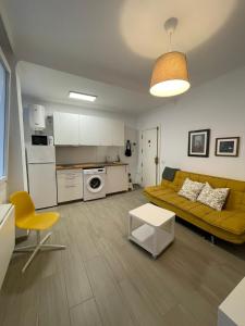 ein Wohnzimmer mit einem gelben Sofa und einer Küche in der Unterkunft A Sunlit Haven, Home in Canarias in Las Palmas de Gran Canaria