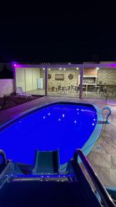 a blue swimming pool at night with tables and chairs at Casa con piscina y barbacoa in Rivera