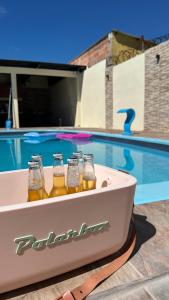 quatro garrafas de cerveja numa banheira ao lado de uma piscina em Casa con piscina y barbacoa em Rivera