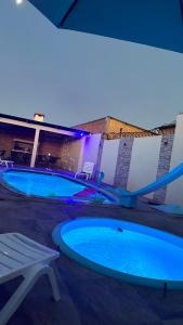 2 piscinas con luces azules en un edificio en Casa con piscina y barbacoa, en Rivera