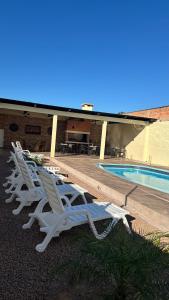 a row of white lounge chairs next to a swimming pool at Casa con piscina y barbacoa in Rivera