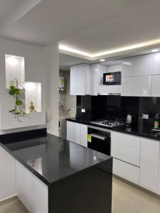 una cucina con armadietti bianchi e ripiani neri di CALI Acogedor y Nuevo apartamento cerca de Jardin plaza, con piscina, parqueadero y aire acondicionado a Cali