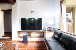 ein Wohnzimmer mit einem schwarzen Ledersofa und einem Flachbild-TV in der Unterkunft Villa Adela in Luque