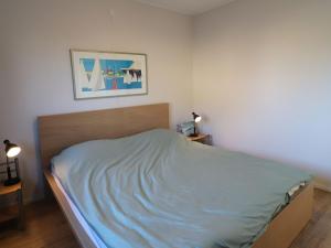 a bedroom with a bed with a blue blanket on it at Sunny apartment directly on the Heegermeer in Heeg