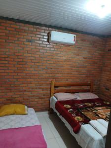 2 camas en una habitación con una pared de ladrillo en Casa em Florianópolis, rio vermelho de 2 quartos bem localizada, en Florianópolis