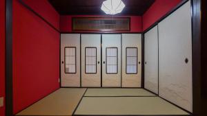 un pasillo con cuatro puertas en una habitación roja en 古都とき Kototoki en Kanazawa