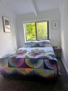 um quarto com uma cama com um edredão colorido e uma janela em The Partchery Devonport em Auckland