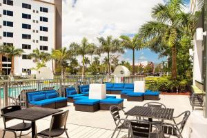 a patio with blue tables and chairs and palm trees at Aloft Miami Doral in Miami