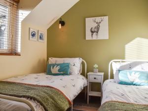 1 dormitorio con 2 camas y una foto de ciervo en la pared en Pike Cottage, en Hinderwell