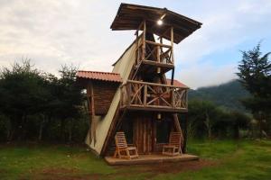 una casa en un árbol con dos sillas en un campo en Fuego - Wood Cabin Tecpan (No Wifi, Relax), en Tecpán Guatemala